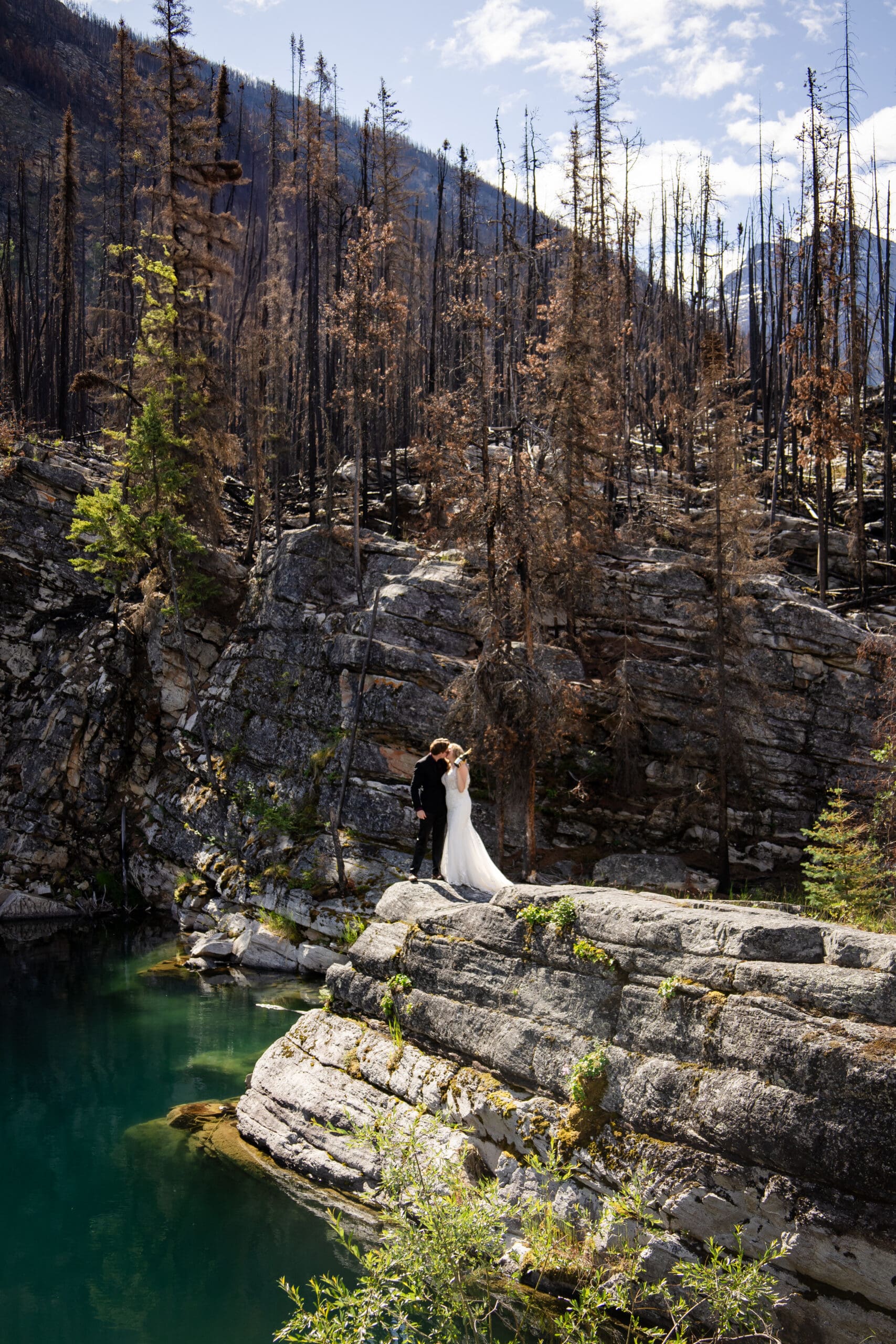 Jasper elopement photographer capturing a couple standing on a rocky cliff above a turquoise river in Jasper National Park.